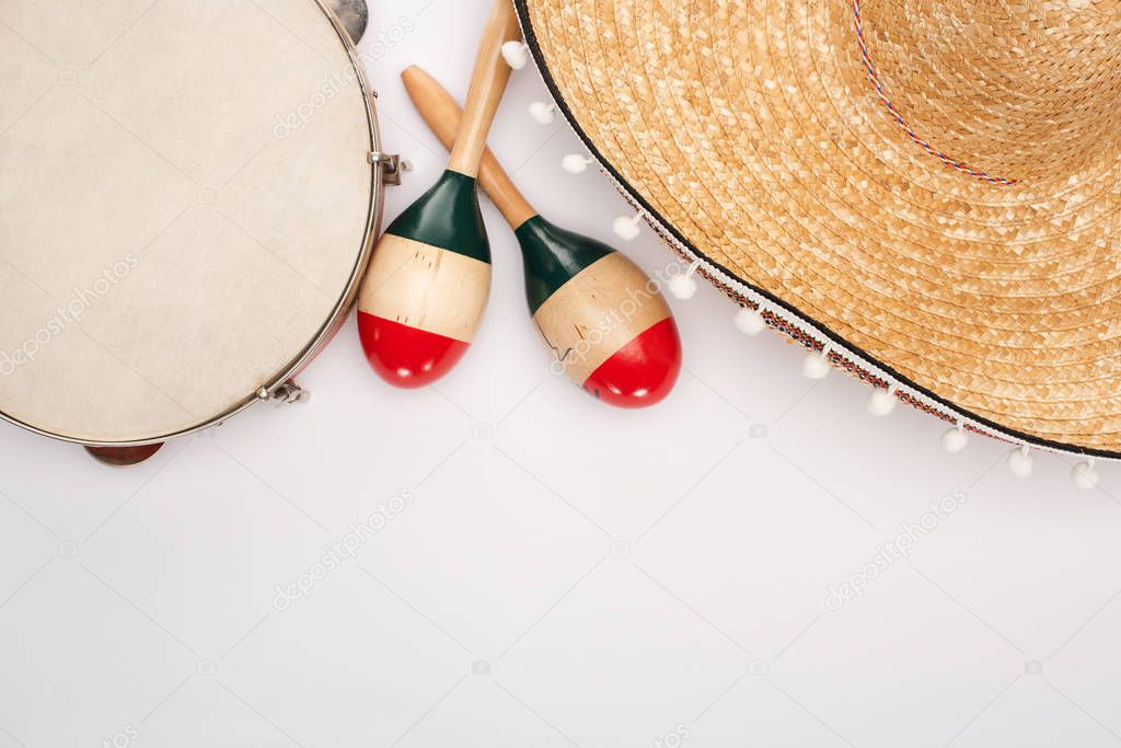 Top view of wooden maracas with tambourine and sombrero on white background