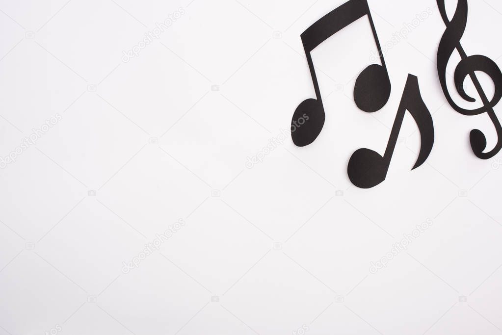 Top view of black paper cut music notes on white background