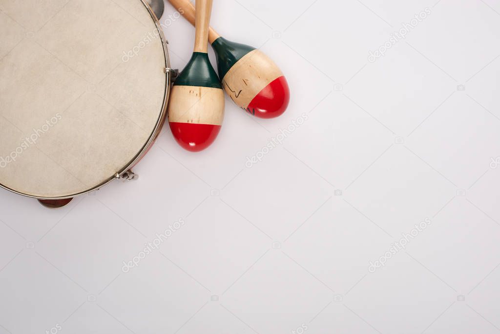 Top view of wooden maracas near tambourine on white background