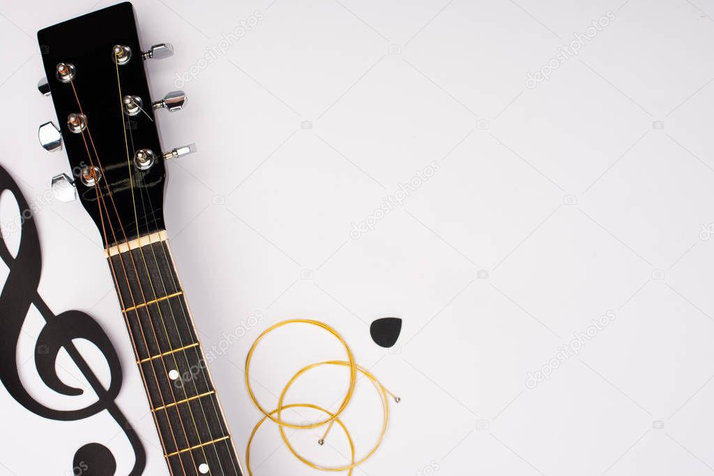 Top view of acoustic guitar and paper cut music note on white background