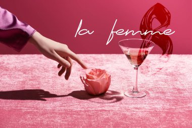 cropped view of woman touching rose near glass with drink on velour cloth isolated on pink, la femme and 8 march illustration