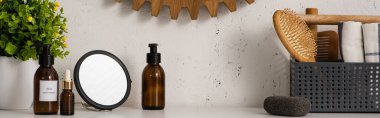 Kozmetik ürünlerin yanında tarak, saç fırçası ve havluyla panoramik manzara ve banyoda saksı, sıfır atık kavramı