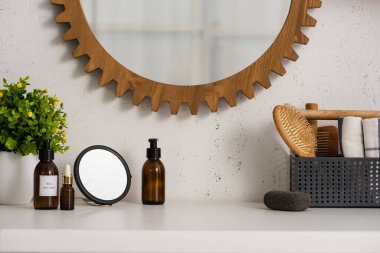 Kozmetik ürünlerinin yanında tarak, saç fırçası ve havlularla dolu bir kutu ve banyoda saksı, sıfır atık kavramı.