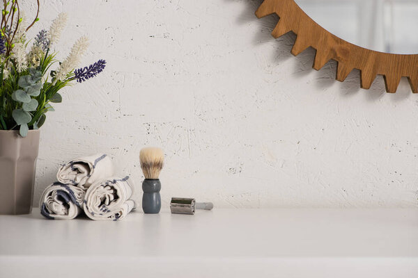 Flowerpot, towels, shaving brush and razor near mirror on wall in bathroom, zero waste concept