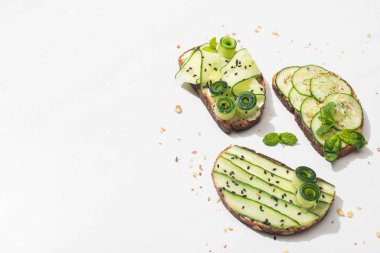 Taze salatalıklı tost, beyaz arka planda nane ve fesleğen yaprakları.
