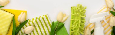 Bahar lalelerinin üst görüntüsü, beyaz arka planda yeşil ve sarı temizlik malzemeleri, panoramik çekim