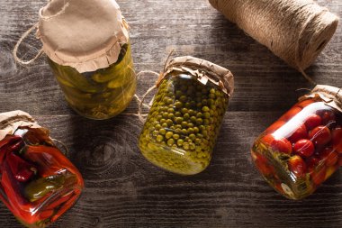 top view of homemade delicious pickles in jars on wooden table clipart