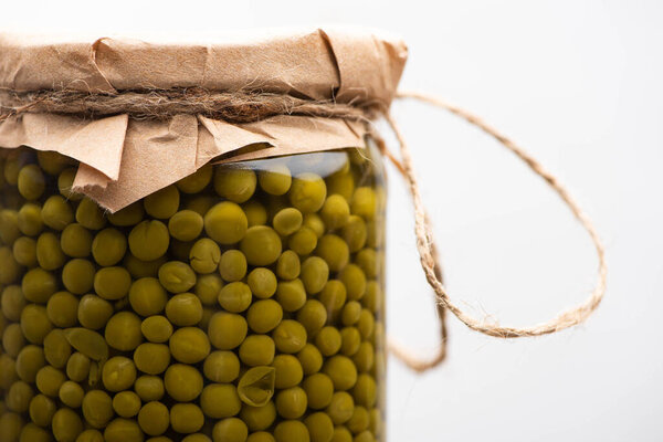 close up view of homemade tasty canned green peas in jar isolated on white