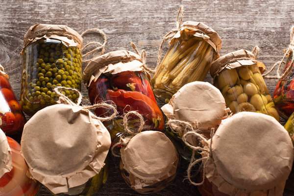 top view of delicious pickles in jars on wooden table