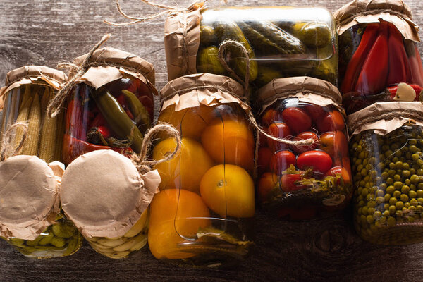 top view of delicious pickles in jars on wooden table