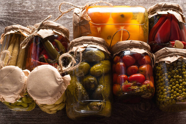 top view of delicious pickles in jars on wooden table