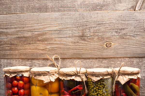 top view of tasty homemade pickles in jars on wooden rustic table with copy space