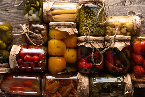 top view of delicious pickles in jars on wooden table