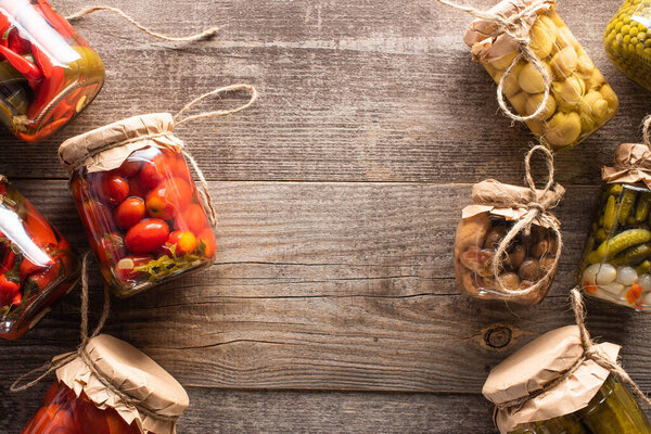 top view of homemade tasty pickles in jars on wooden table with copy space