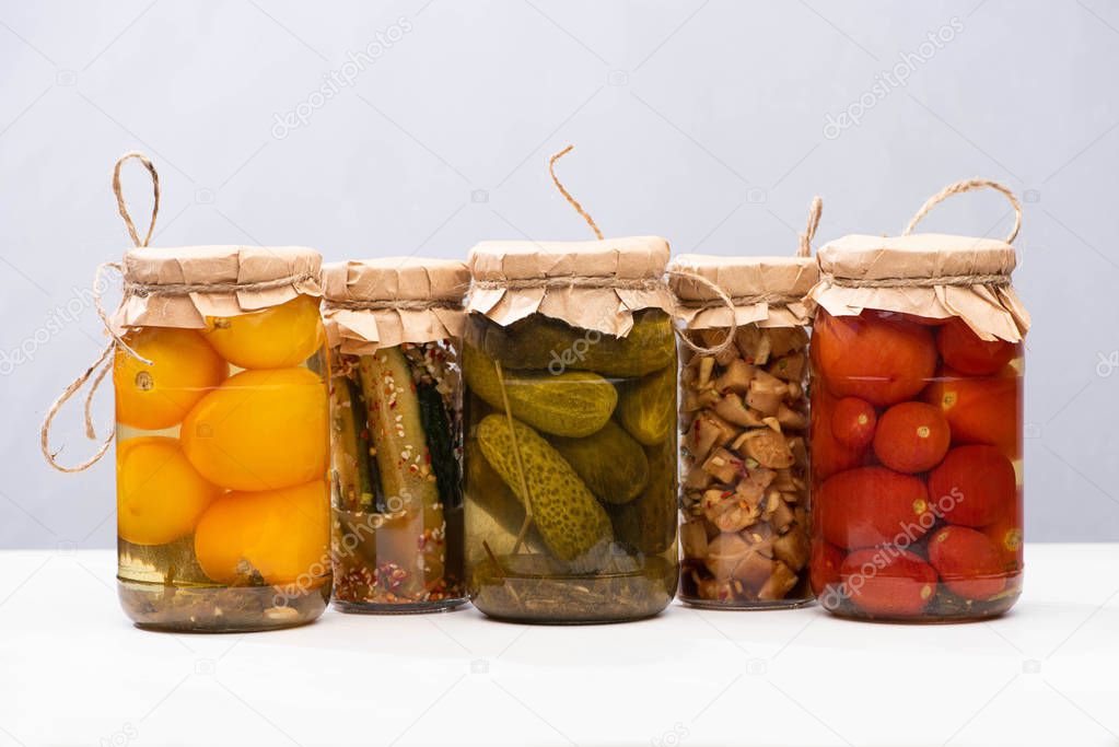 rustic homemade tasty pickles in jars isolated on grey