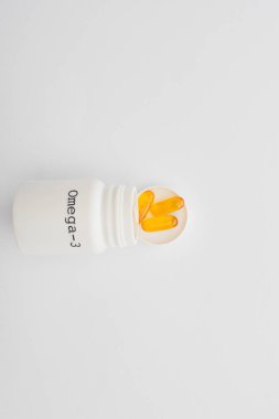 Beyaz arkaplan üzerinde omega-3 kapsülleri olan açık konteynırın üst görünümü