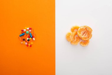 Top view of colorful medicines and mandarin on white and orange background clipart