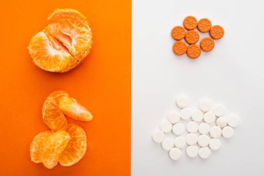 Top view of dietary supplements and mandarin on white and orange clipart