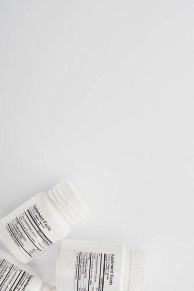 Top view of containers with dietary supplements on white background