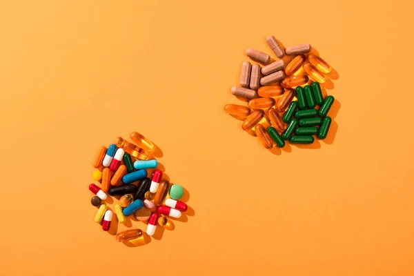 橙色背景的彩色药丸和胶囊的顶部视图 — 图库照片
