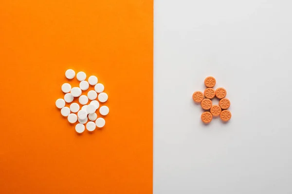 白とオレンジの背景に丸薬のトップビュー — ストック写真