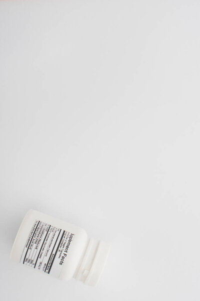 Top view of container with dietary supplements on white