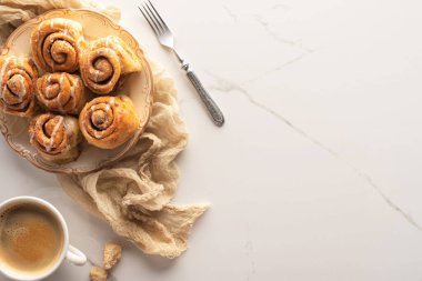 Kahve, çatal ve bezle mermer yüzeyde taze ev yapımı tarçın rulolarının üst görüntüsü