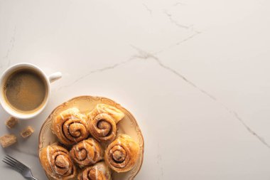 top view of fresh homemade cinnamon rolls on marble surface with cup of coffee, fork and brown sugar clipart