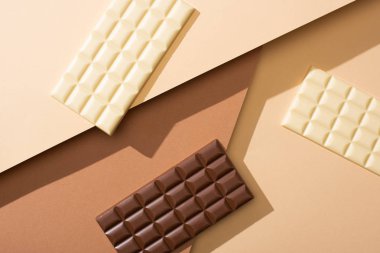 top view of delicious whole white and milk chocolate bars on beige background clipart
