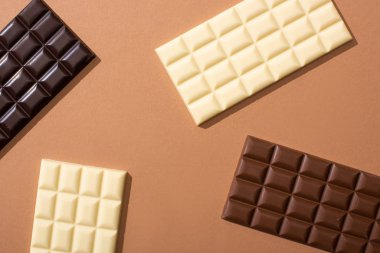 top view of delicious whole milk, white and dark chocolate bars on dark background clipart