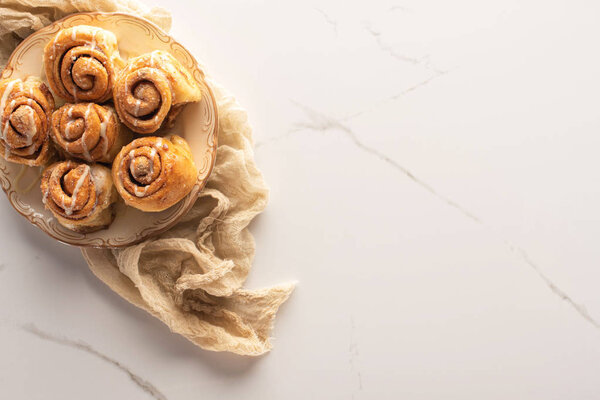 top view of fresh homemade cinnamon rolls on marble surface with cloth