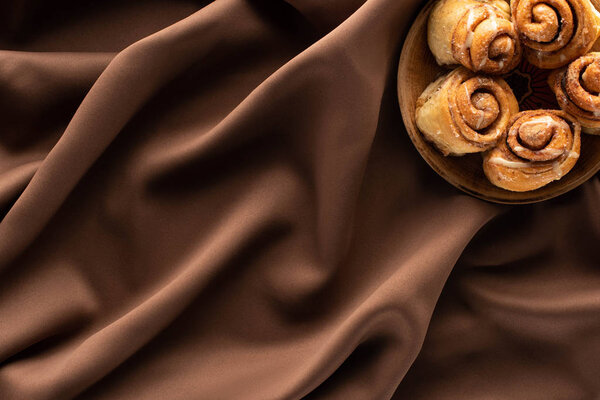 top view of fresh homemade cinnamon rolls on silk brown cloth