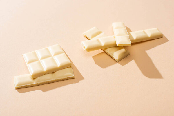 sweet delicious broken white chocolate bar on beige background