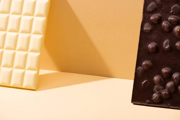 Köstliche Gebrochene Weiße Und Dunkle Schokoladentafeln Mit Nüssen Auf Beigem — Stockfoto