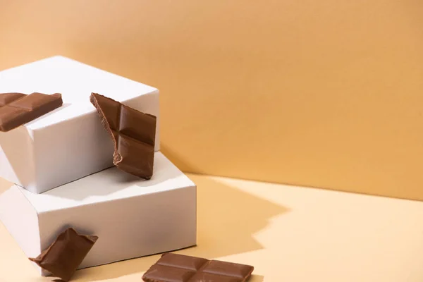 Läckra Mjölk Choklad Bitar Och Fyrkantiga Kuber Beige Bakgrund — Stockfoto
