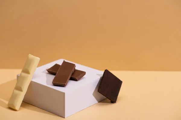 ベージュを背景にしたおいしいホワイト ダーク ミルクチョコレートとキューブ — ストック写真
