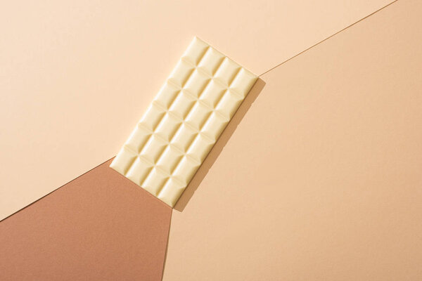 top view of delicious whole white chocolate bar on beige background