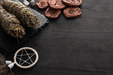 Bitkisel leke çubukları, düş kapanı ve kara tahta arka planda kil tılsımlar.