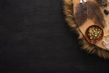 Tüyleri, kuru çiçekleri ve siyah ahşap arka planda kristalleri olan şamanik tef manzarası