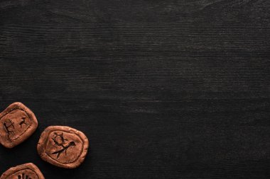 Siyah ahşap arkaplanda sembolleri olan kil tılsımların üst görünümü
