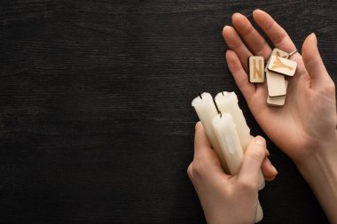 Elinde rünler olan şamanların en üst görüntüsü. Koyu ahşap arka planda mumlar.