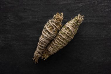 Top view of herbal smudge sticks on dark wooden background clipart