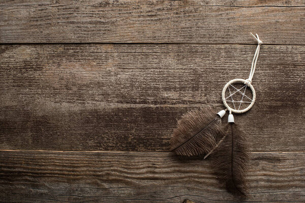 Top view of dreamcatcher with feathers on wooden background