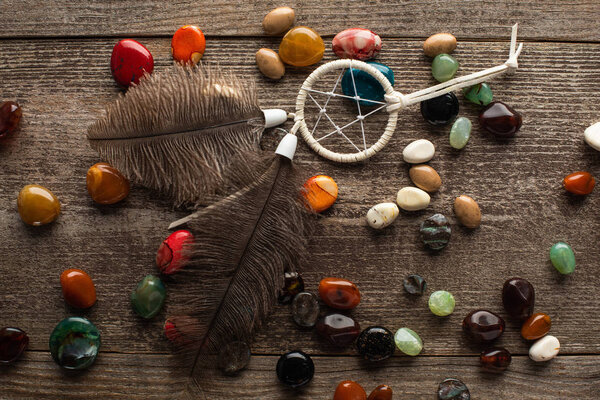 Top view of shamanic dreamcatcher on fortune telling stones on wooden surface