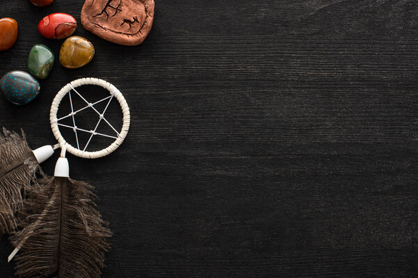 Top view of dreamcatcher, fortune telling stones and magic rune on dark wooden background