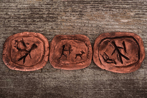 Top view of clay talismans with symbols on wooden background