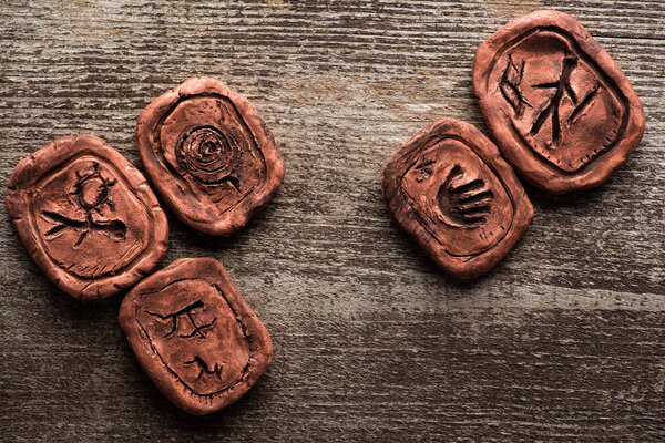 Top view of shamanic clay amulets with signs on wooden surface