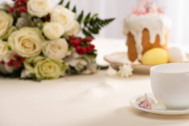 Lezzetli Paskalya pastası ve çiçeklerin yanında bir fincan çayın seçici odağı