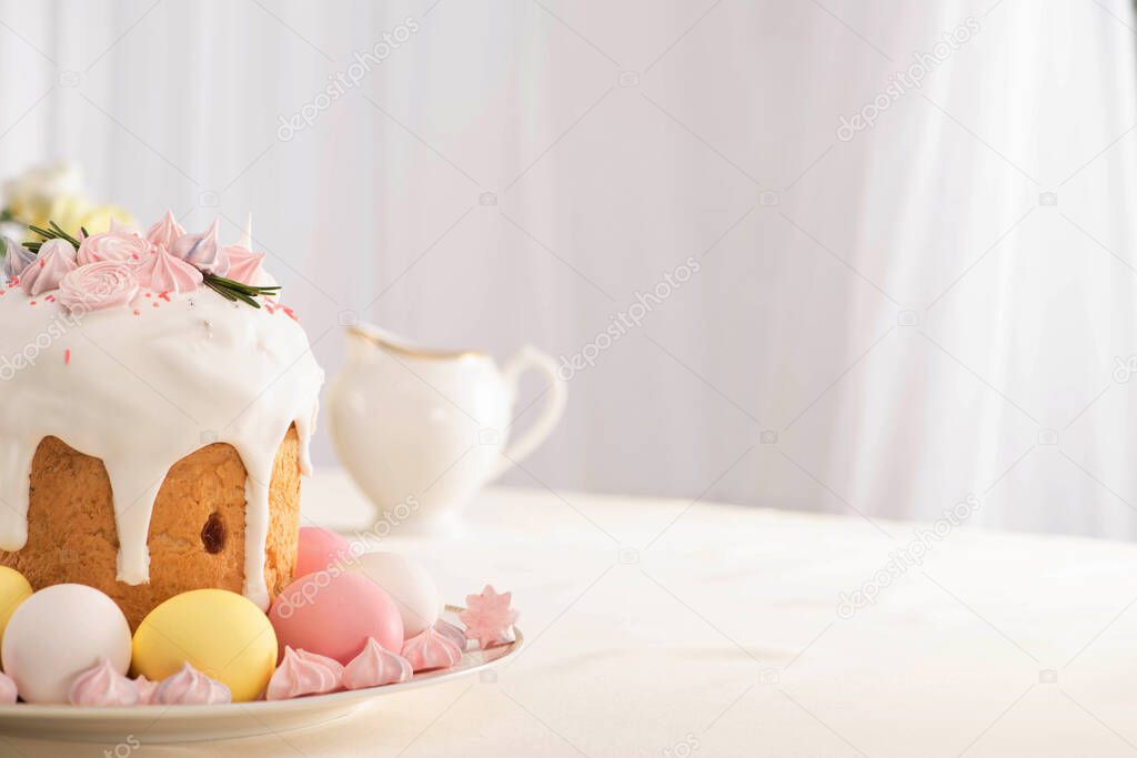 delicious Easter cake decorated with meringue near colorful eggs on plate