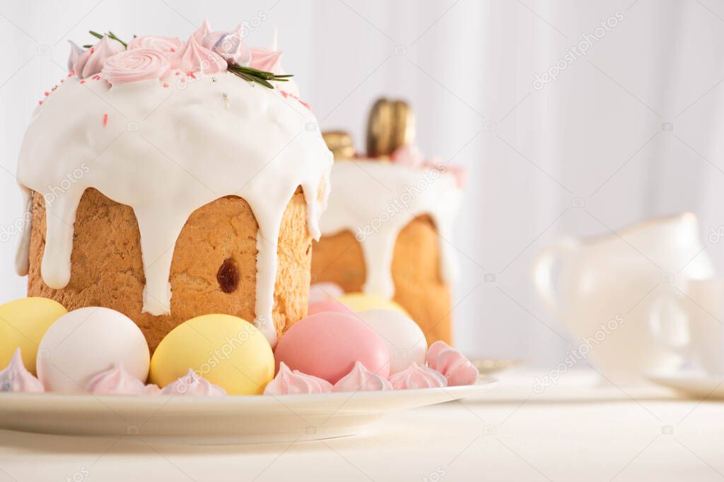 selective focus of delicious Easter cakes decorated with meringue near colorful eggs on plates